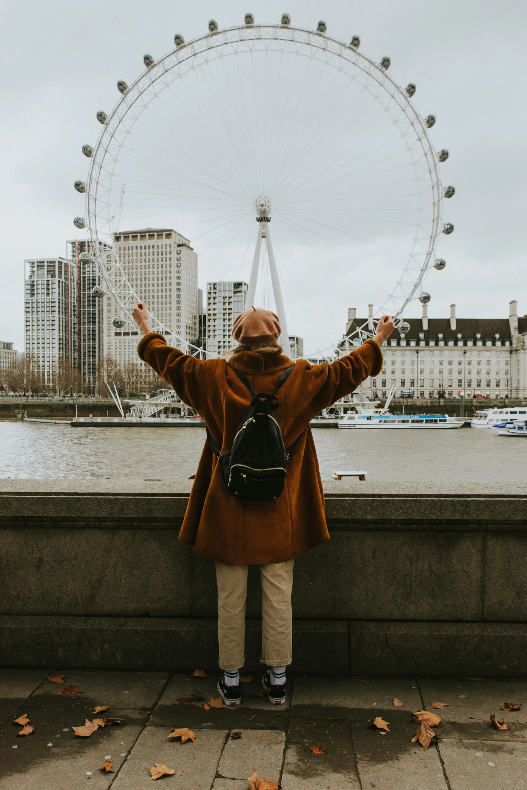 Woman standing with her arms open overlooking the London eye. 