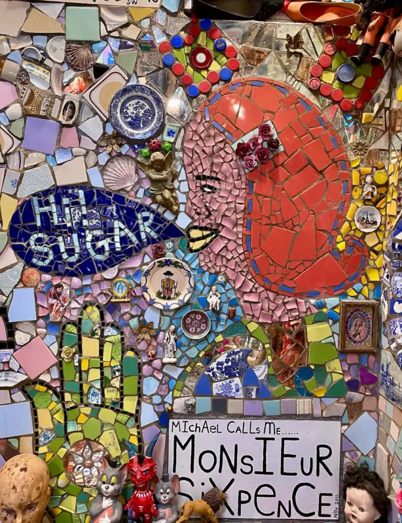 Broken-tile mosaic of a red-haired woman saying โHun Sugarโ above a โMonsieur Sixpenceโ sign at House of Dreams, East Dulwich